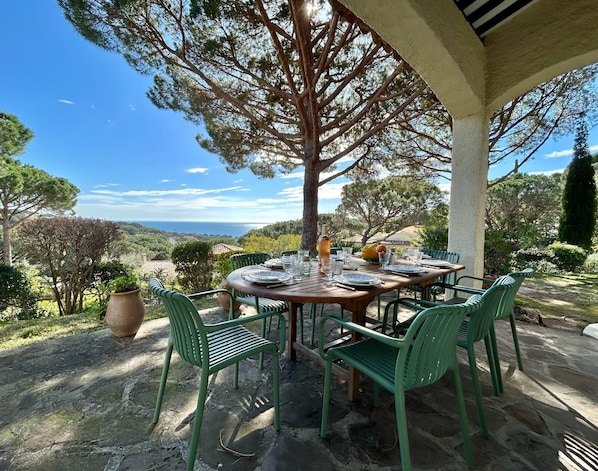 An outdoor dining area with a table set for four, surrounded by green chairs, under a tree. - Dream villa with sea view and pool - family-friendly (Sainte-Maxime)