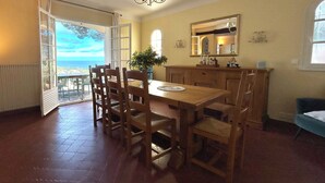 A dining area with a table and chairs, a chandelier, a view through a glass door, and a mirror on the wall. - Dream villa with sea view and pool - family-friendly (Sainte-Maxime)