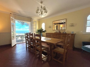 A dining area with a table and chairs, a chandelier, a view through a glass door, and a mirror on the wall. - Dream villa with sea view and pool - family-friendly (Sainte-Maxime)