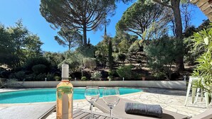 A poolside area with a bottle of wine, a glass, and lounge chairs. - Dream villa with sea view and pool - family-friendly (Sainte-Maxime)