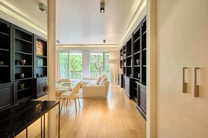 A modern kitchen with black cabinetry, a marble countertop, and a dining area with a white sofa and chairs. - Superb 2 bdr apartment Terrace Neuilly-sur-Seine (Neuilly-sur-Seine)