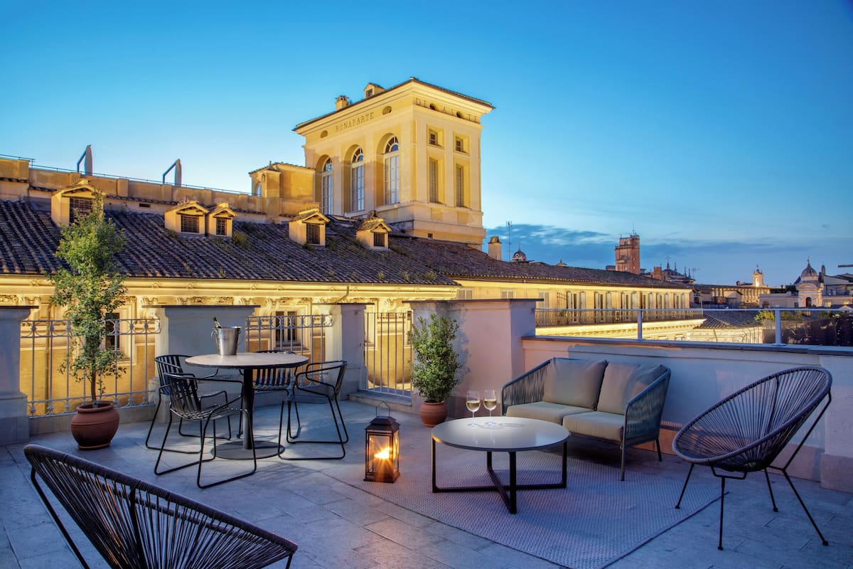 A rooftop terrace with outdoor seating, a potted plant, and a lantern.