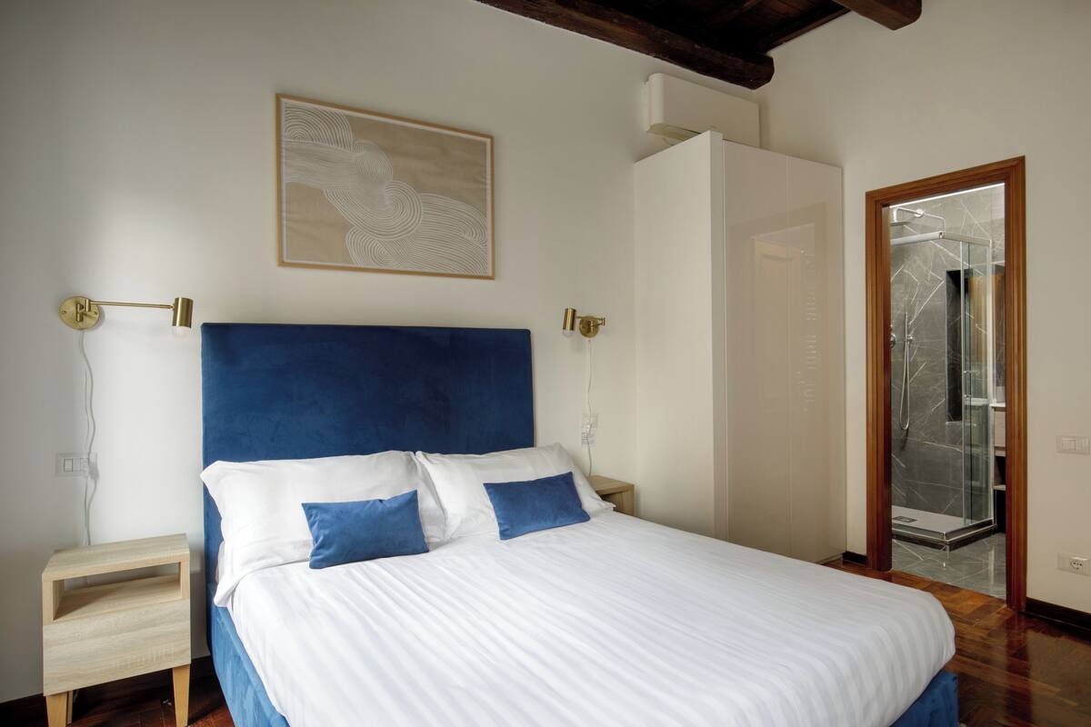 A bedroom with a bed, bedside table, and a door leading to a bathroom.