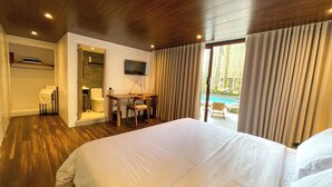 A hotel room with a large bed, a desk with a chair, a TV, and a view of an outdoor pool. - Tagaytay Haven Ulat Managed by Novella (Tagaytay)