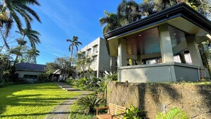A modern building with a covered outdoor area, a stone wall, and a grassy pathway. - Tagaytay Haven Ulat Managed by Novella (Tagaytay)