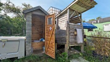 Eine rustikale Holzhütte mit Tür, kleinem Fenster und Metalldach.