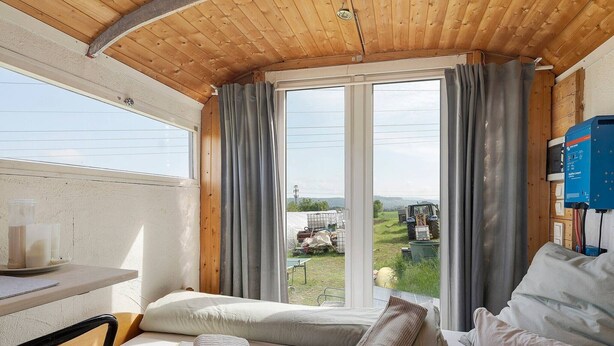 Quarto com uma cama, uma mesa com uma xícara e vista para o exterior.
