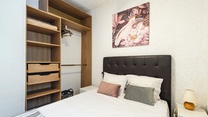 Ein Schlafzimmer mit Bett, Kleiderschrank, Nachttisch und Wandlampe.