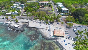 An aerial view of a coastal area with a beach, parking, and buildings. - Sunset View at Kahaluu Bay Villas (Kailua-Kona)