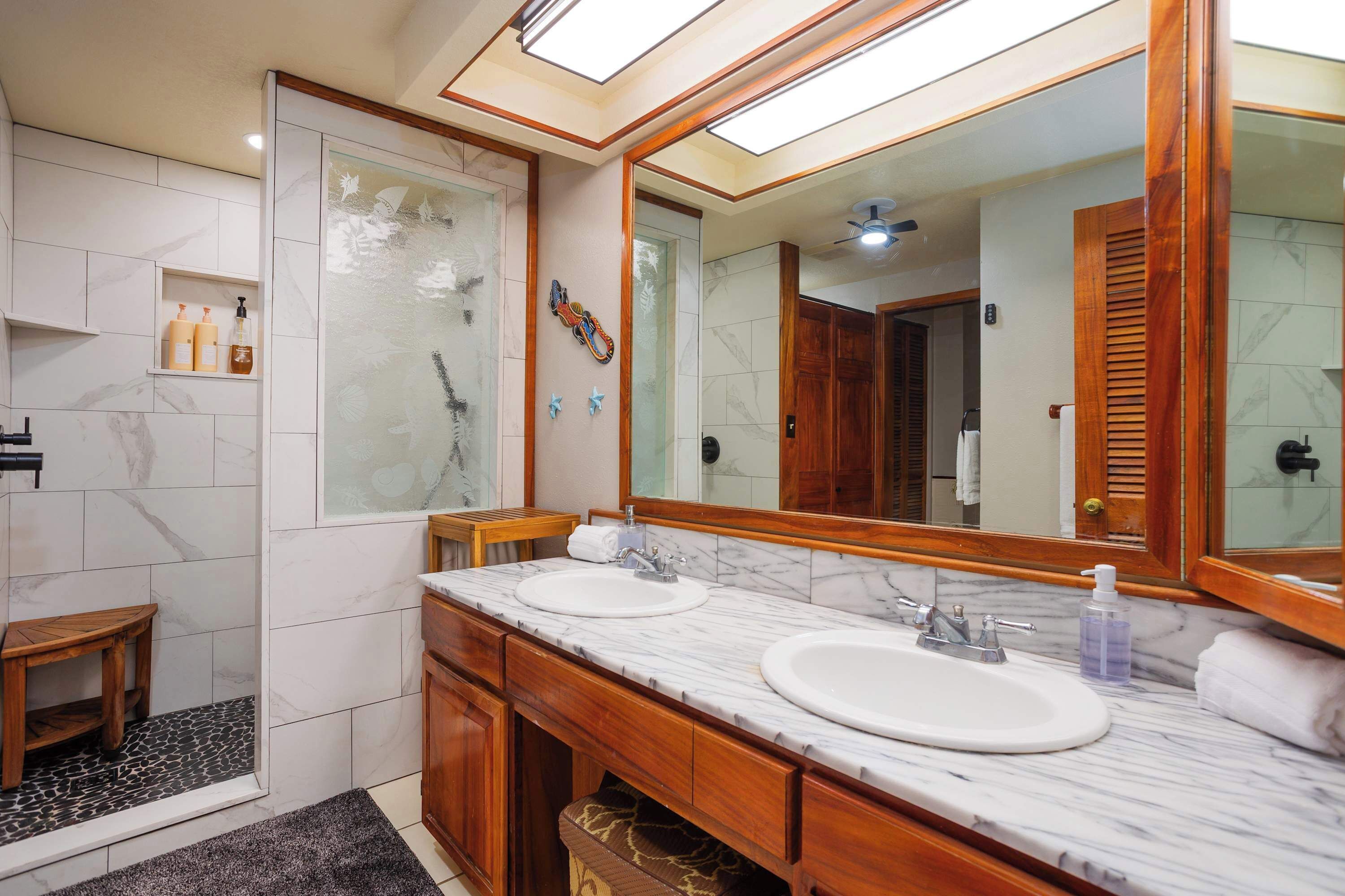 A bathroom with two sinks, a shower, and a large mirror.