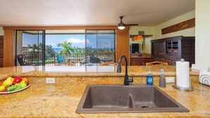 A kitchen with a sink, countertop, and a view of the balcony. - Sunset View at Kahaluu Bay Villas (Kailua-Kona)