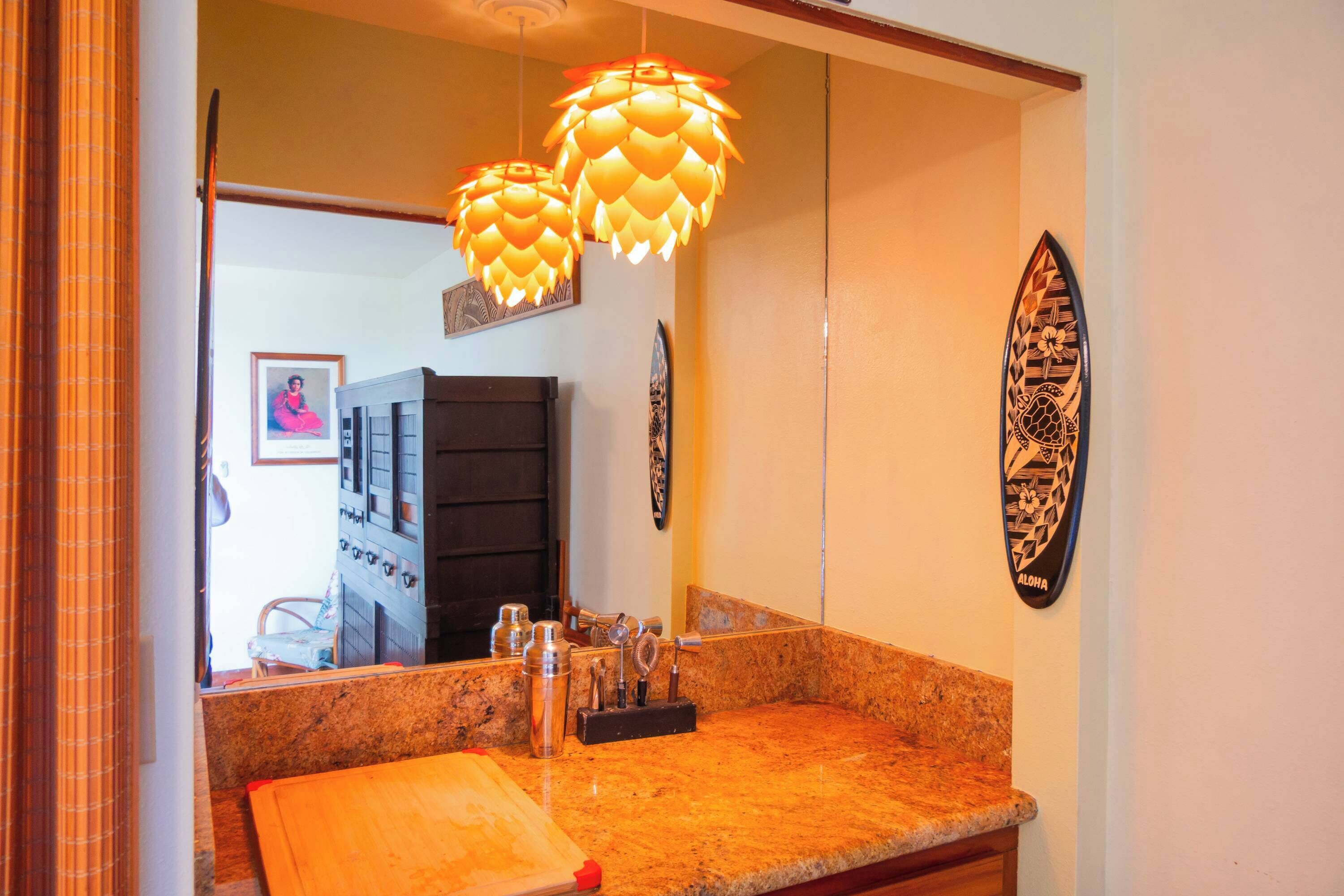 A kitchen with granite countertops, a cutting board, a sink, and a hanging decorative light fixture.