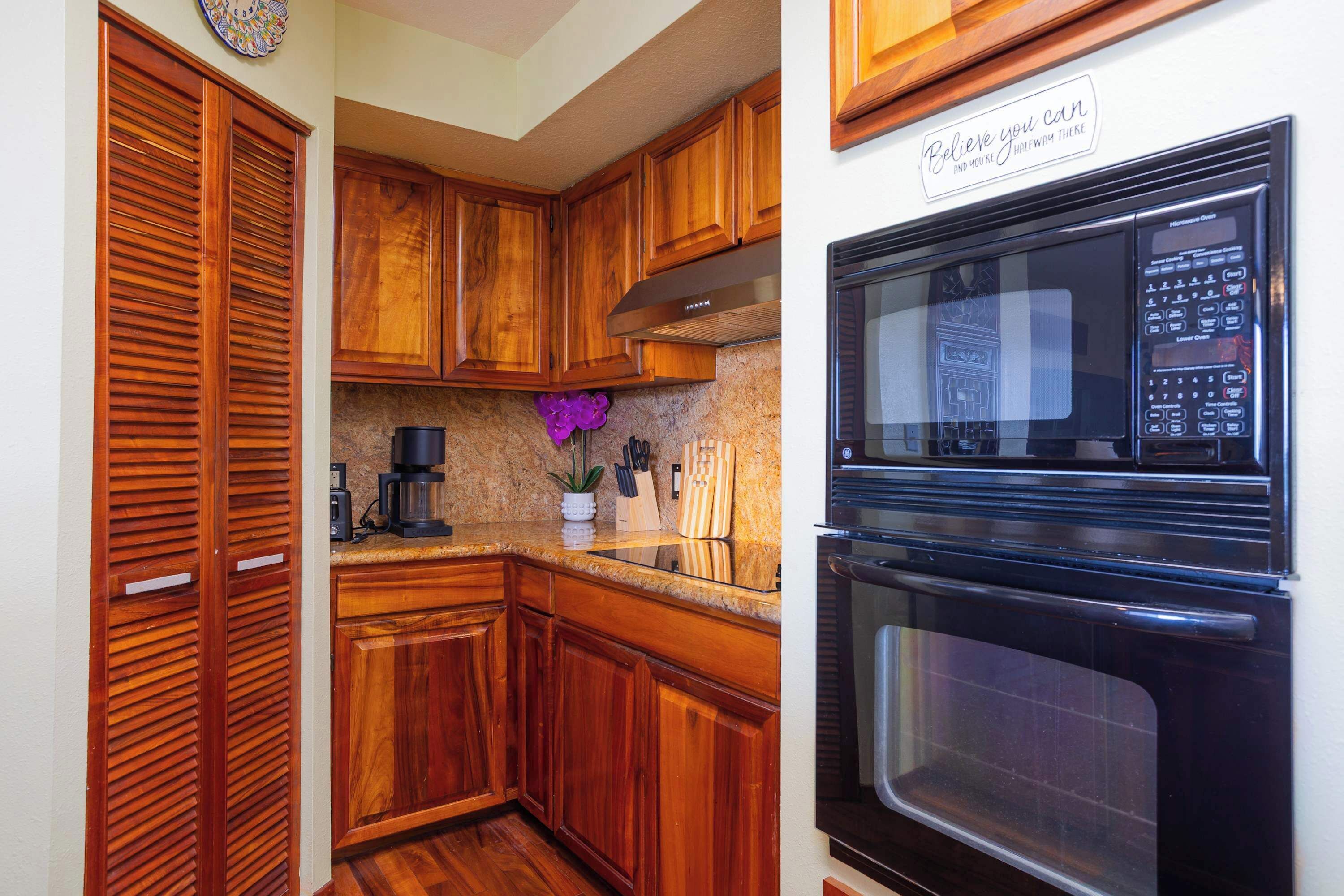 A kitchen with wooden cabinets, a built-in oven, and a coffee maker.
