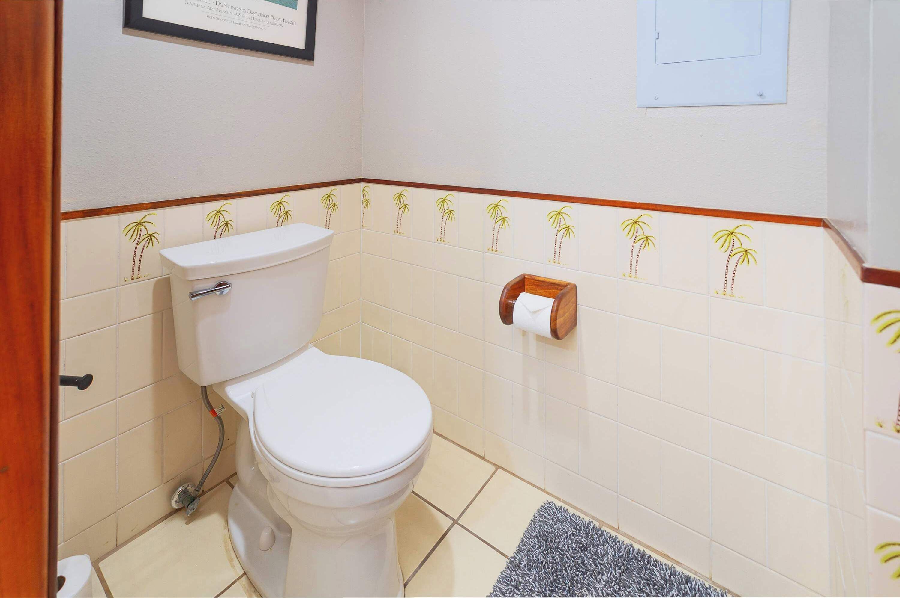 A bathroom with a toilet, a towel dispenser, and a framed certificate on the wall.