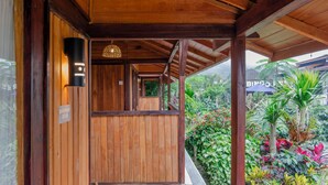 A wooden structure with a sign reading 'BIRUAN 8606' and a view of a lush garden with various plants and a blue umbrella. - Kampung Bingo Glamping & Resto (Baturiti)