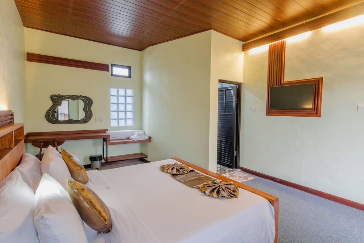 A hotel room with a bed, a mirror, a television, and a window.