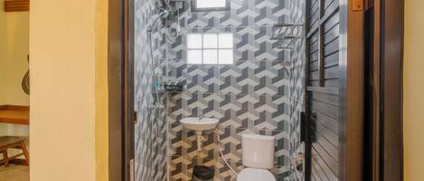 Un baño pequeño con inodoro, lavamanos y ducha.