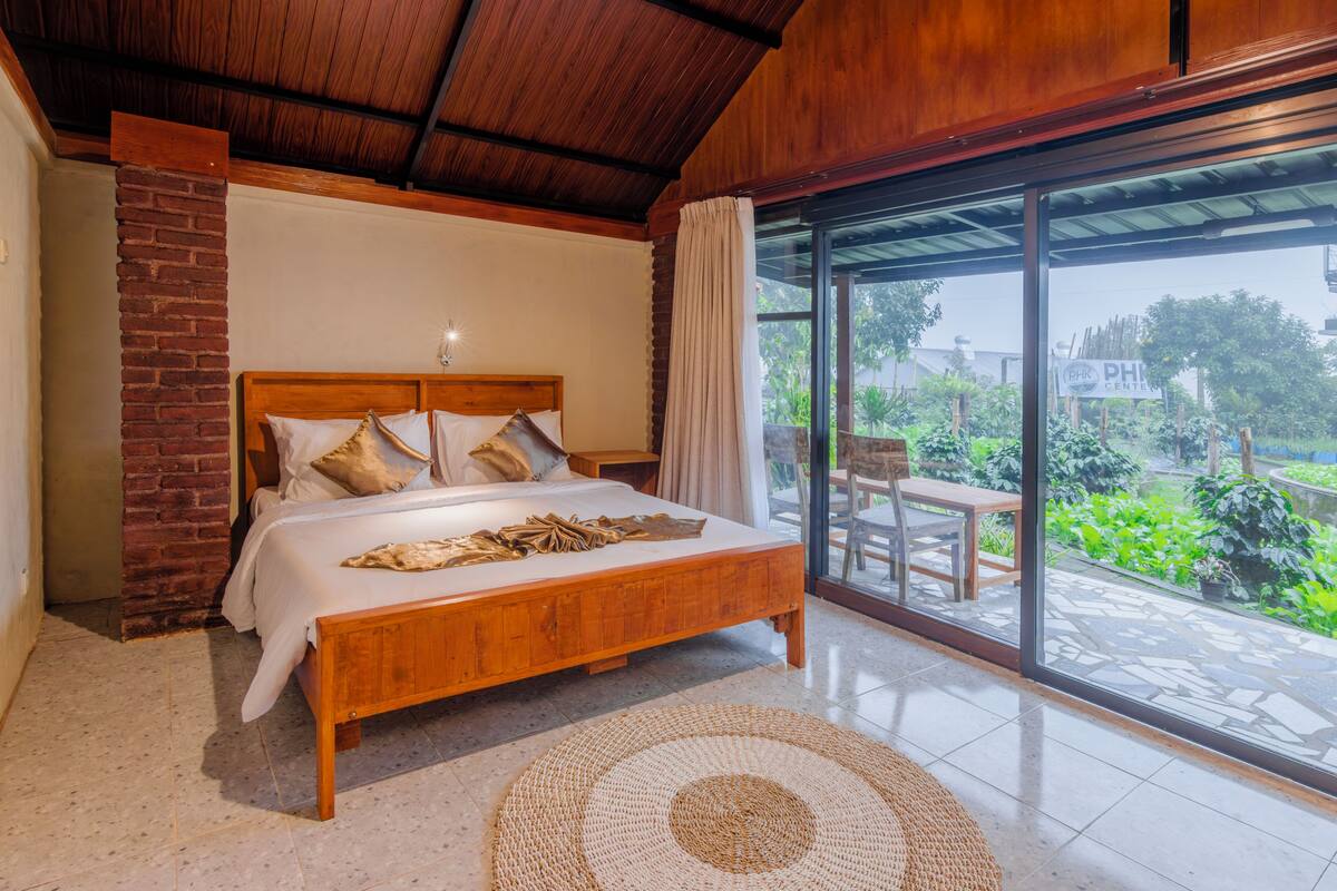 A bedroom with a wooden bed, a brick wall, and a large sliding glass door leading to a patio.