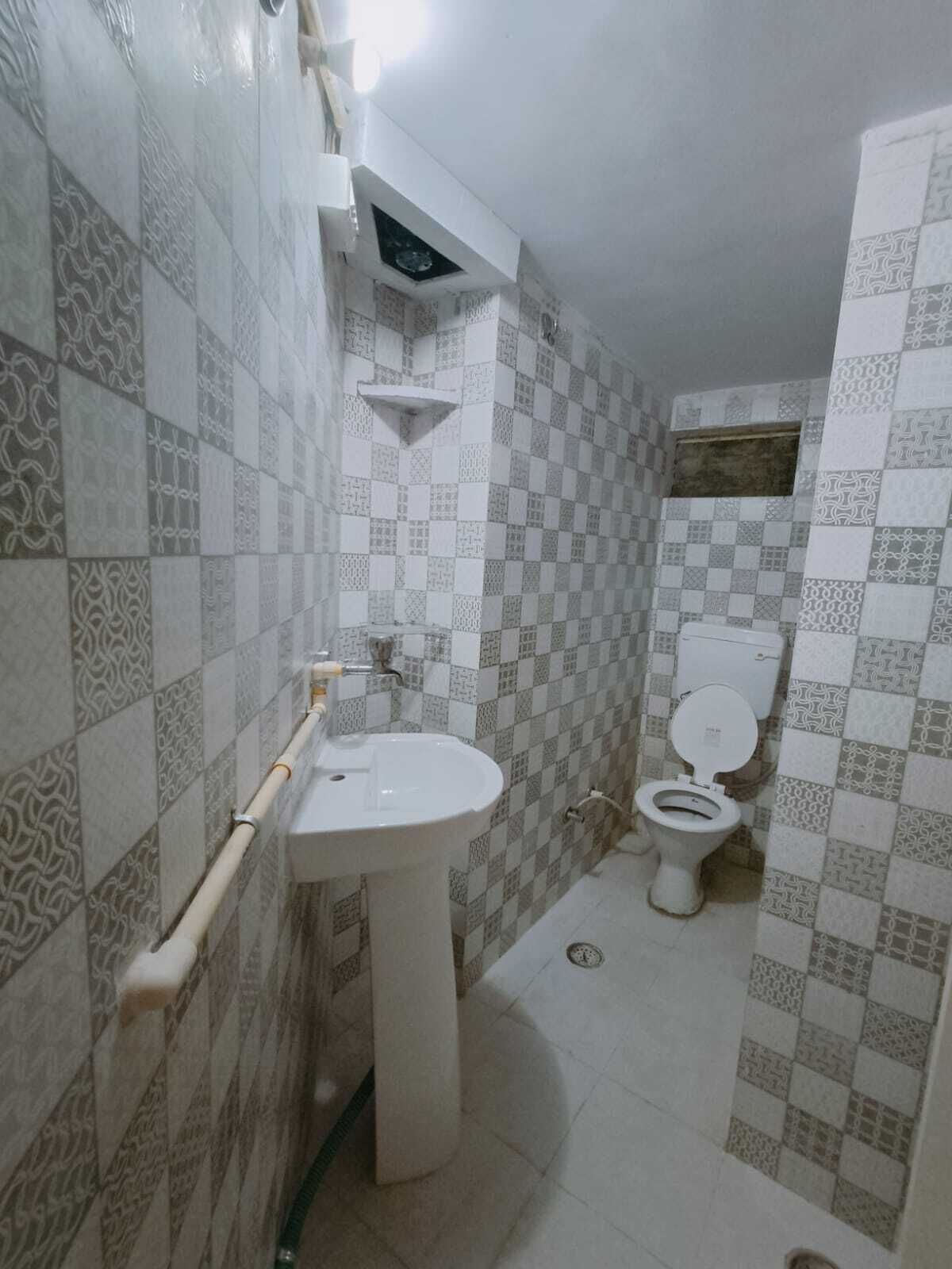 Un baño con lavamanos, inodoro y azulejos estampados.