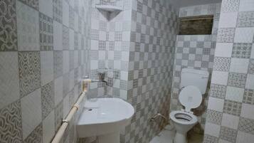 Un baño con lavamanos, inodoro y azulejos estampados.