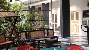 An outdoor dining area with a table, chairs, and hanging lights. - Homestay Urmil Basant (Jaipur)