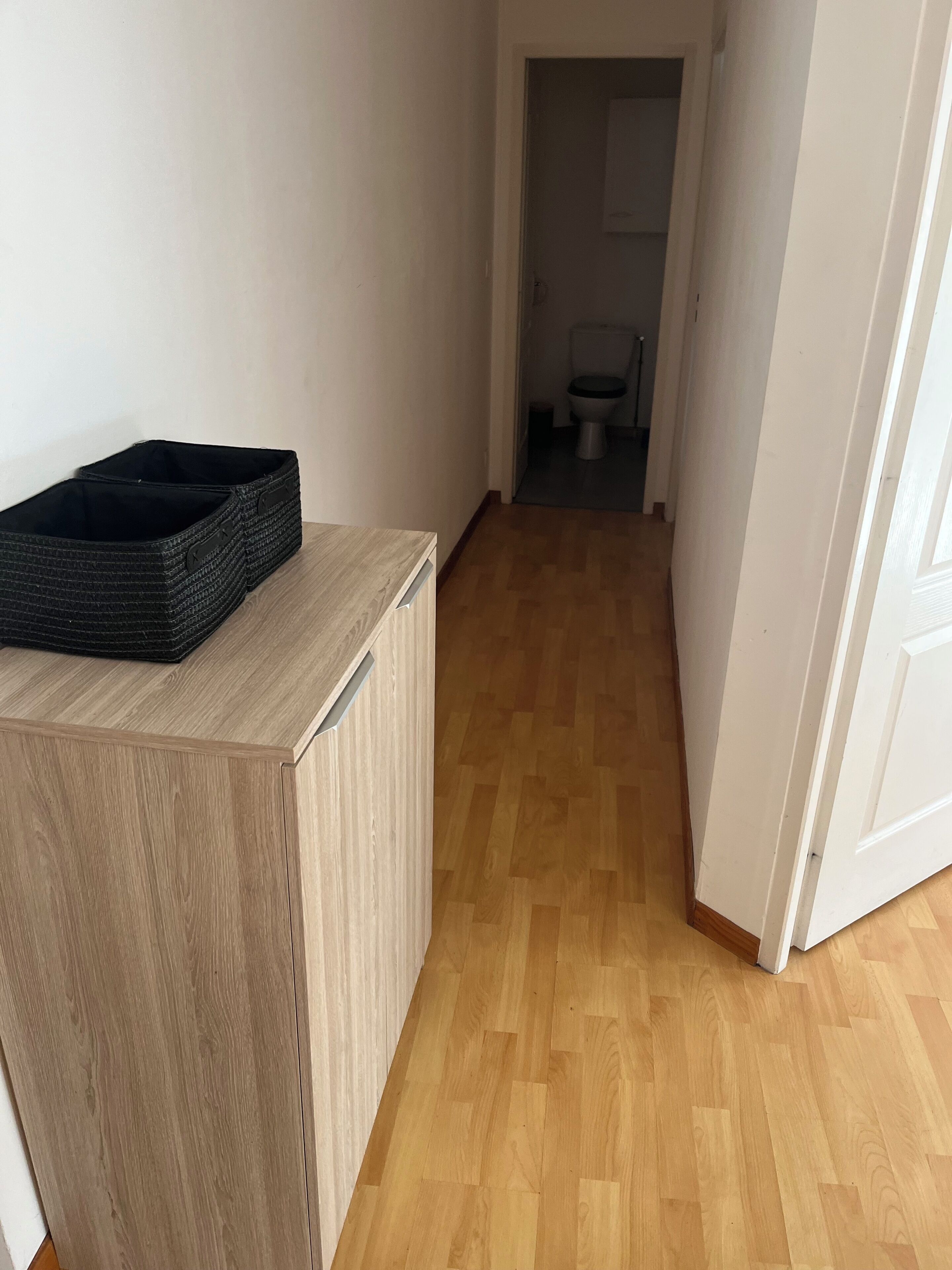 Un couloir au plancher de bois menant à une salle de bain.