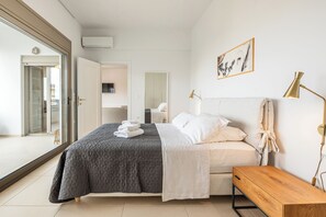 Un dormitorio moderno con cama, mesita de noche y vistas a través de una puerta de cristal.