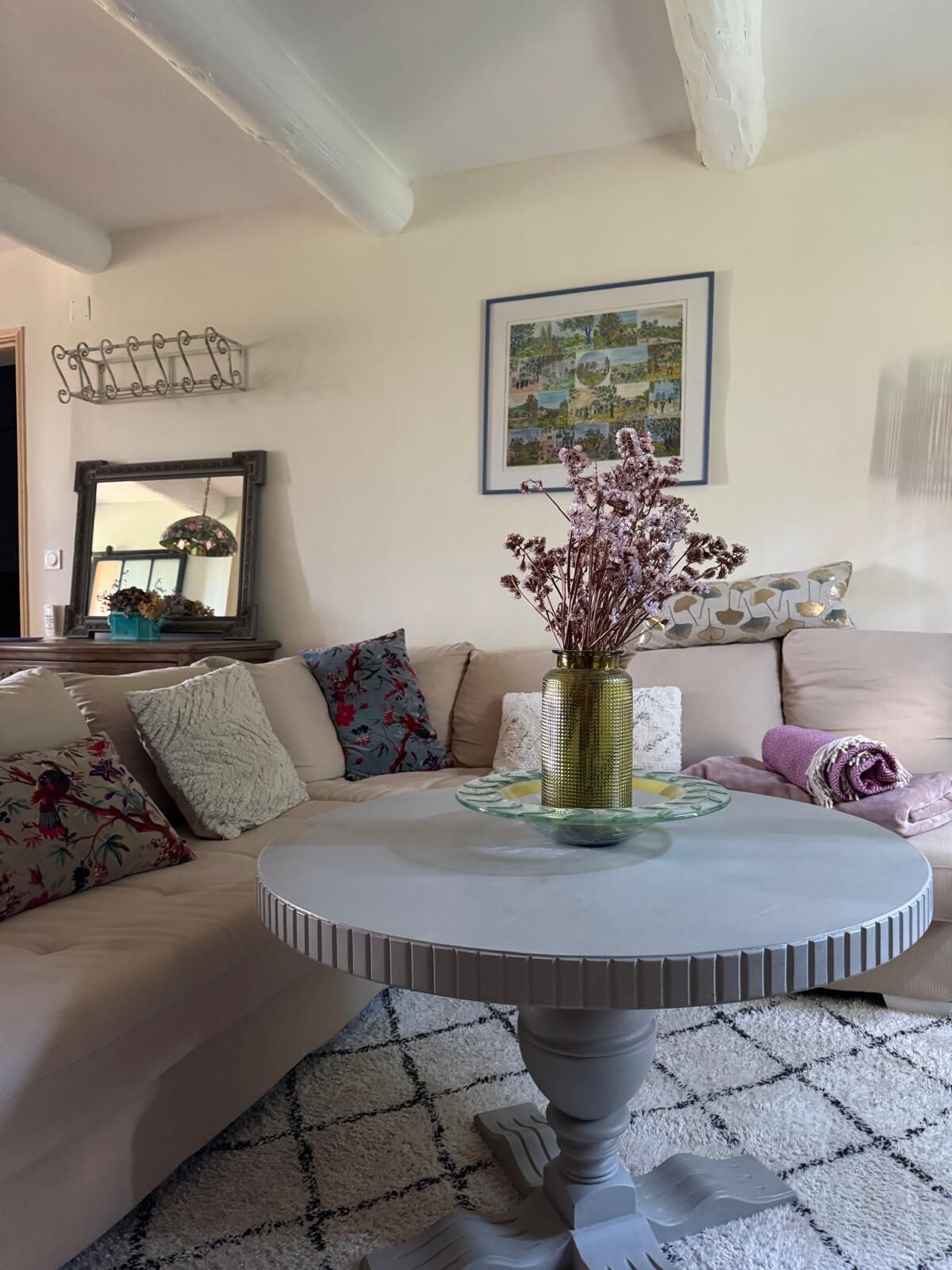 Een woonkamer met een ronde salontafel, een bloemenvaas en een kamerbreed tapijt.
