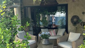 A cozy outdoor seating area with wicker furniture, a patterned rug, and a potted plant.