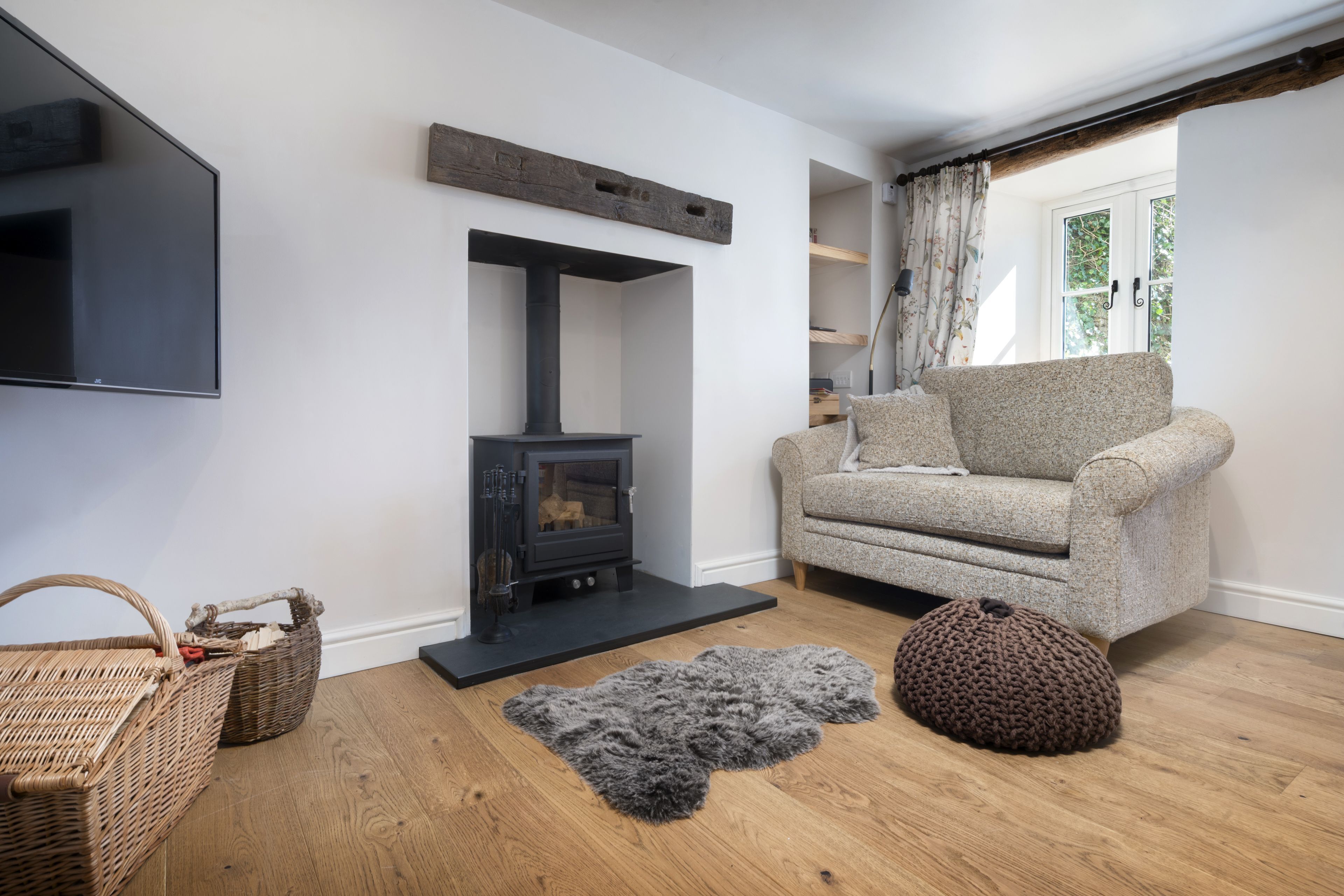 A living room with a fireplace, a sofa, a rug, and a wooden floor.