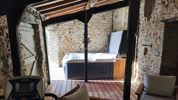 Una terraza de madera con sauna, paredes de piedra y un panel de control.