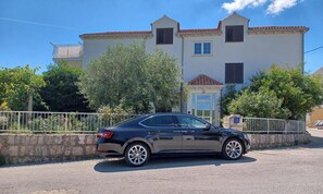 A black car parked in front of a building with a tiled roof and multiple windows. - Above the Blue: 2BR Tranquil Horizon Pool&Terrace (Bosanka)