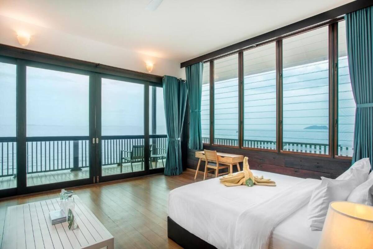 A hotel room with a large bed, a desk, and a view of the sea.
