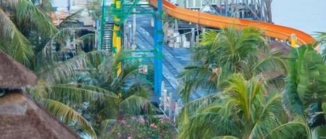 Un parc aquatique doté d’un grand toboggan et d’une structure recouverte d’un toit de chaume.