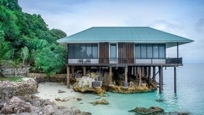 A modern house with a balcony, situated on a rocky shore with clear water. - Rawa Island Resort (Mersing)