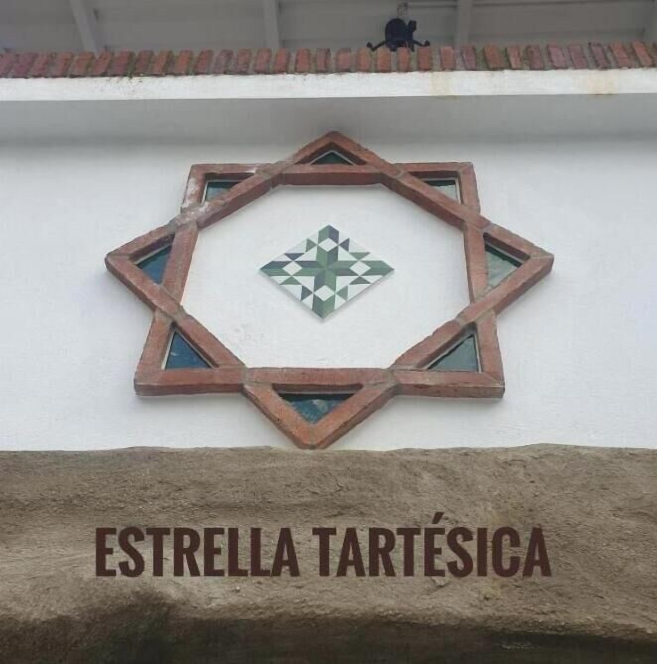 Ein fensterförmiges Design mit einem Sternmuster in der Mitte und der Aufschrift 'ESTRELLA TARTÉSICA' darunter.