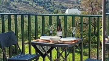Un balcon avec une table dressée pour deux personnes, une bouteille et un verre.