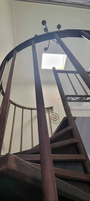 A spiral staircase with a metal handrail and a skylight above. - Wonderland Art House 2BR Loft Melville Walk to 7th With Secure Parking (Johannesburg)