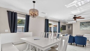 Een moderne eethoek met een witte tafel, stoelen en een kroonluchter.