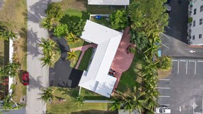 An aerial view of a property with a central building, surrounded by palm trees and a parking area. - Coconut Oasis Near Beach (Lauderdale-by-the-Sea)