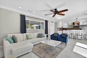 A modern living room with a sofa, chairs, a coffee table, and a ceiling fan. - Coconut Oasis Near Beach (Lauderdale-by-the-Sea)