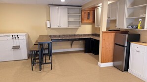 Una cocina equipada con refrigerador, pileta y taburetes de bar.