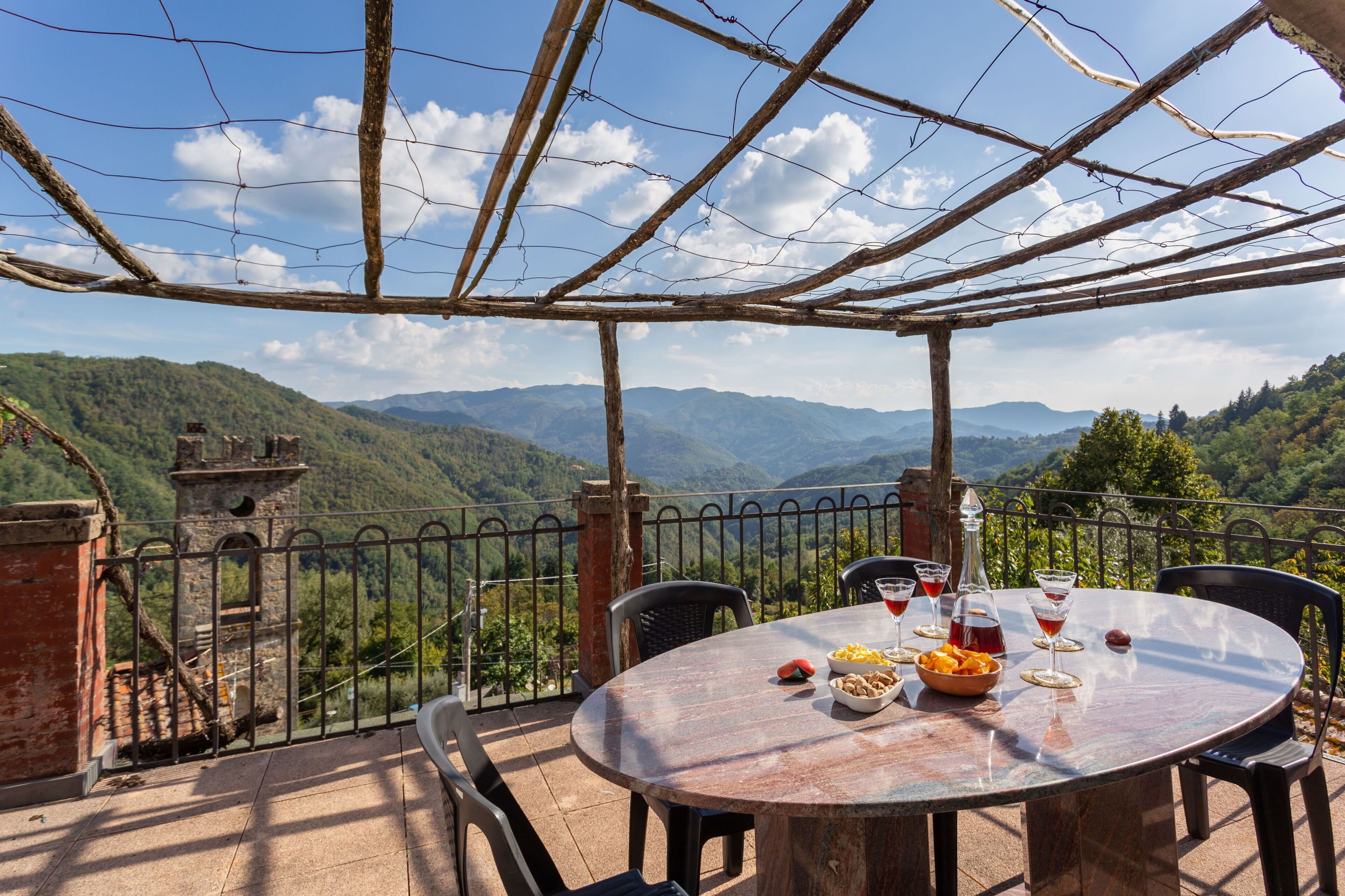 Una mesa con comida y bebidas, vista a las montañas y una estructura de pérgola.