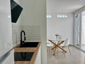 Una cocina moderna con un grifo negro, salpicadero de azulejos blancos y encimera de madera.