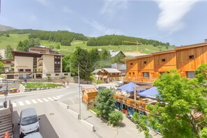 A town with buildings, a road, and a hilly landscape. - Apartment 'Appart 2 Alpes, Centre Station' with Mountain View and Wi-Fi (Les Deux Alpes)