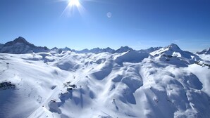 Eine verschneite Berglandschaft mit blauem Himmel und fernen Gipfeln.