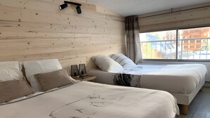 Ein Hotelzimmer mit zwei Betten, einer Holzwand, einem Fenster mit Aussicht und einer Deckenleuchte.