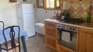 Une cuisine avec des meubles de rangement en bois, un réfrigérateur, une cuisinière et une table à manger avec des chaises.