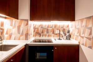 Una cocina con lavavajillas integrado, un fregadero y una encimera con salpicadero de azulejos geométricos.