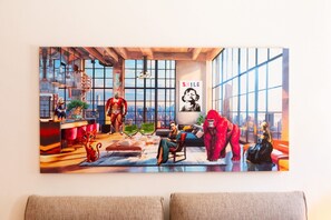 Un quadre gran que mostra una habitació amb vista a una ciutat, un sofà, una cadira i un gat.